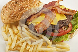 A delicious cheese burger with bacon and french fries