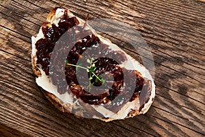 Delicious French Appetizer Freshly Cooked Onion Confit on toast with cream cheese and thyme. Wood board and jar with