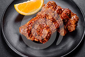 Delicious fresh baked pork ribs with orange on a black plate