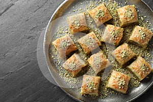 Delicious fresh baklava with chopped nuts on grey table, top view and space for text. Eastern sweets