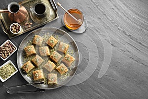 Delicious fresh baklava with chopped nuts served on grey table, flat lay and space for text. Eastern sweets