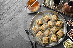 Delicious fresh baklava with chopped nuts served on grey table, flat lay and space for text. Eastern sweets