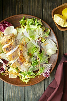 Delicious fresh caesar salad with grilled chicken on wooden table, flat lay vertical image