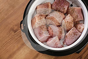 Delicious fresh chicken with spices in modern multi cooker on wooden table. Space for text