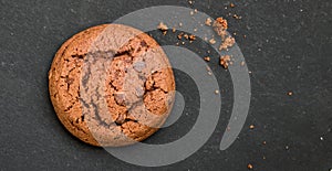 Delicious fresh chocolate cookie with small crumbs lies on a dark background
