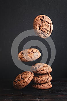 Delicious fresh chocolate cookies stacked on a wooden dark table