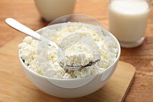 Delicious fresh cottage cheese in bowl on wooden table, closeup