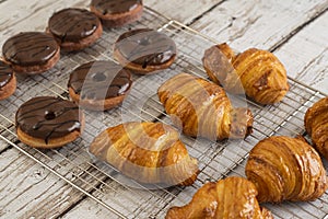 Delicious, fresh croissants and chocolate Donuts on a grid, French breakfast