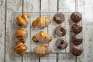 Delicious, fresh croissants and chocolate Donuts on a grid, French breakfast