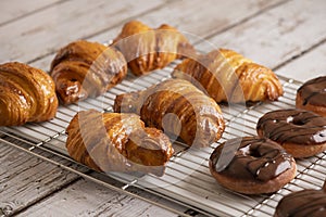 Delicious, fresh croissants and chocolate Donuts on a grid, French breakfast