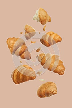 Delicious fresh croissants falling on beige background