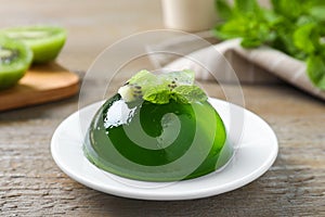 Delicious fresh green jelly with kiwi slices and mint on table