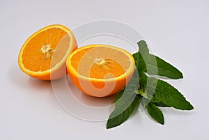 Healthy ripe delicious fruits for human health. Juicy fruits of orange orange with bright green mint. Two halves of an orange with