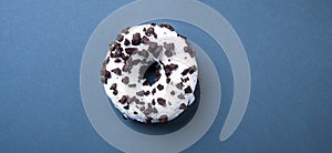 Delicious fresh hearty black and white donut lies on a classic blue background. Jank food and high-calorie food
