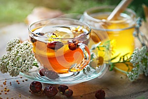 Delicious fresh honey and a Cup of healthy tea with lemon and rose hips on a wooden table. Selective focus.