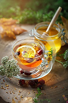 Delicious fresh honey and a Cup of healthy tea with lemon and rose hips on a wooden table. Selective focus.