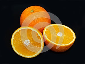 Delicious fresh juicy whole and halved oranges on black background