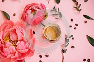 Delicious fresh morning espresso coffee with eucalyptus leaves, coral peony flowers and coffee beans on the tender pink background