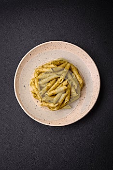 Delicious fresh pasta penne with green pesto sauce with basil, salt and spices
