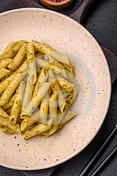 Delicious fresh pasta penne with green pesto sauce with basil, salt and spices