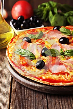 Delicious fresh pizza on brown wooden background.