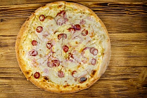 Delicious fresh pizza with sausage, red onion and cheese on wooden table. Top view