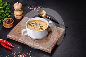 Delicious fresh pumpkin puree soup decorated with parsley in a white plate