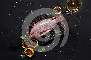 Delicious fresh raw red seafood fish mullet on dark table, top view
