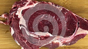 Delicious fresh rib eye beefsteak filmed directly from above on wooden cutting board ready for being cooked for dinner