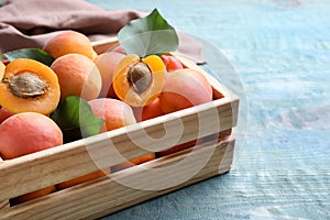 Delicious fresh ripe apricots in crate on wooden table, closeup