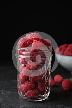 Delicious fresh ripe raspberries in glass jar on table