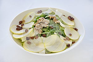 Delicious fresh salad with crispy apples, earthy walnuts, rocket leaves and a handful of raisins, healthy and vegan eating