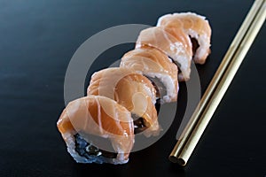 Delicious fresh sushi rolls with salmon and cream cheese on black plate. Traditional japanese food, healthy food concept