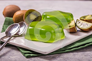Delicious fresh two green jelly with kiwi slices on concrete table