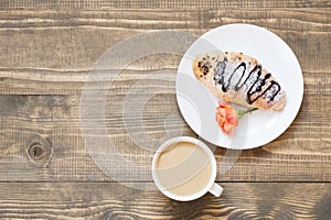 Freshly baked chocolate croissants and cup of coffee on wooden board. Top view. Female breakfast concept. Copy space.