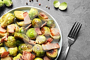 Delicious fried Brussels sprouts with bacon served on grey table, flat lay