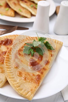 Delicious fried cheburek with cheese and parsley on white tiled table, closeup