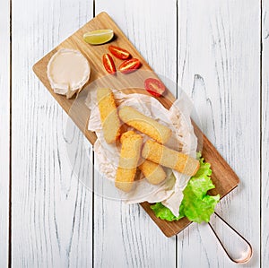 Delicious fried cheese sticks on wooden board.