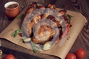 Delicious fried chicken wings lie on the serving board, decorated with various spices , herbs and vegetables.