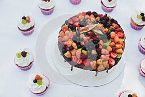 Delicious fruit cake with cupcakes for a happy birthday.