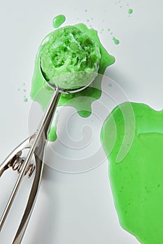 Delicious fruit ice cream in a scoop with splashes and drops on a gray background with copy space. Top view