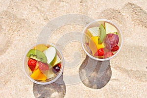 Delicious fruit salad in plastic cup on beach
