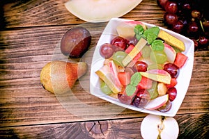 Delicious fruit salad, vegetarian food in bowl on rustic table