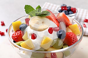 Delicious fruit salad with yogurt in bowl on table, closeup