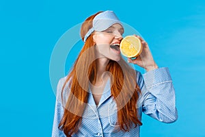 Delicious fruit starting morning healthy. Waist-up portrait attractive sleepy, pretty redhead girl in sleep mask and