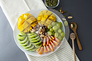 Delicious fruits platte isolated. Mango, kiwi, citrus, nuts, grapes. Mix of various exotic fruits. Healthy fruit salad