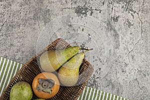 Delicious fuyu persimmon and ripe pears in wicker basket