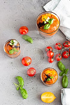 Delicious gazpacho soup in glass. Traditional spanish cold soup puree gaspacho garnish with tomato, cucumber and basil. Grey