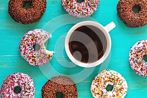 Delicious glazed donuts and cup of coffee on turquoise surface