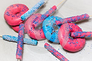 Delicious glazed donuts with sprinkles and candy sticks on light background